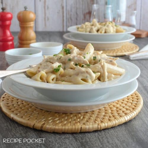 A creamy garlic parmesan chicken pasta slow cooker dish in a white serving plate.