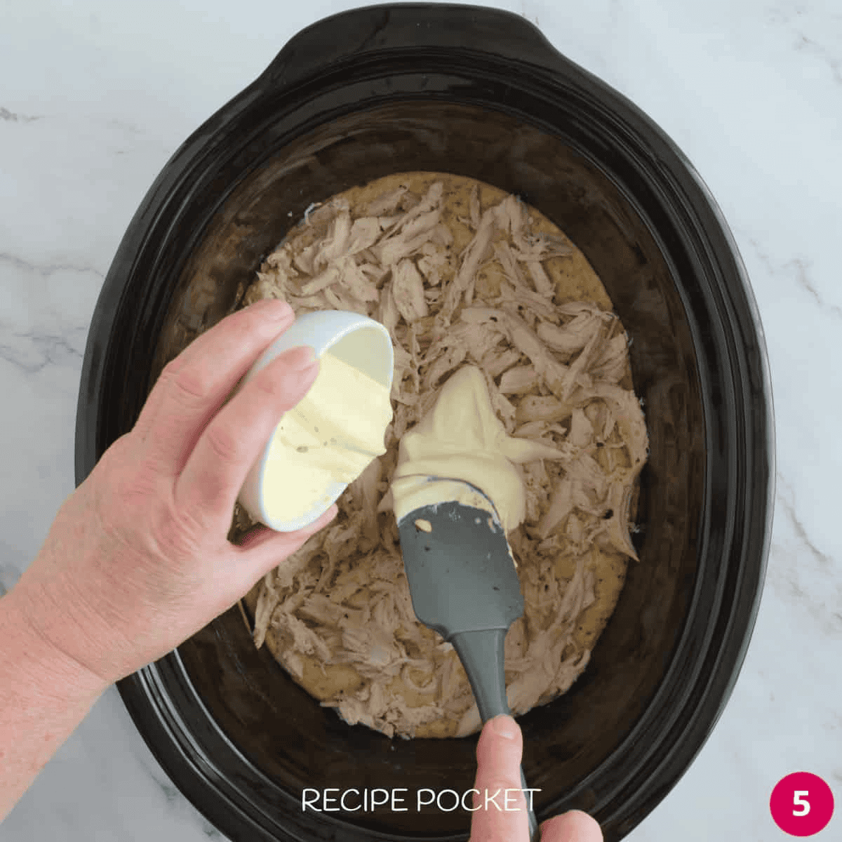 Sour cream being added to slow cooker bowl. with shredded chicken.
