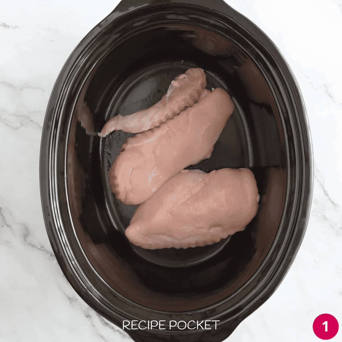 Chicken breast pieces in a slow cooker bowl.