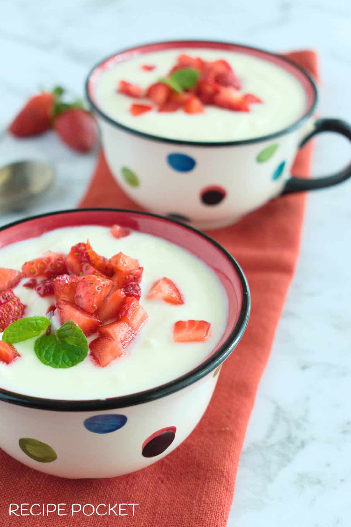 Two cups of yogurt and strawberries.