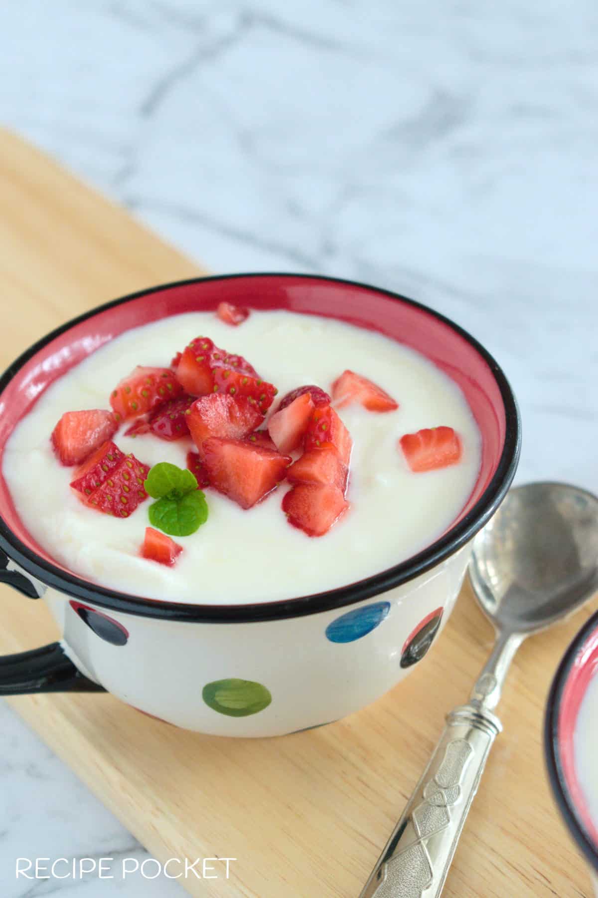 One cup of yogurt on a wooden board.
